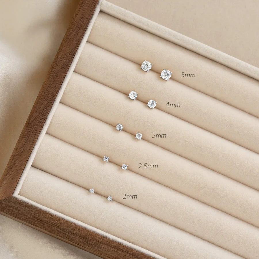 Diamond stud earrings in five sizes displayed on a velvet jewelry tray.