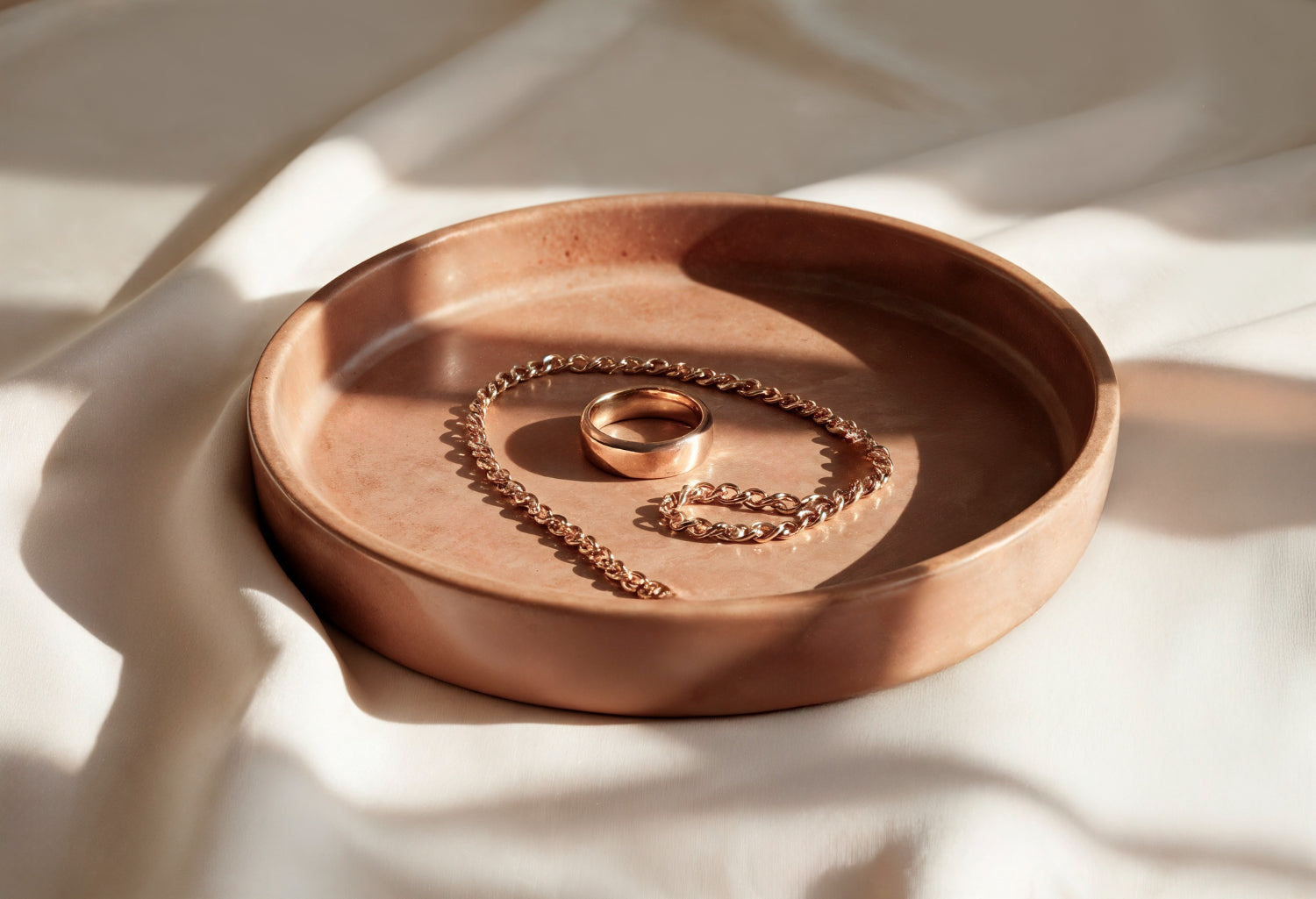 copper jewelry in a wooden bowl over a cloth