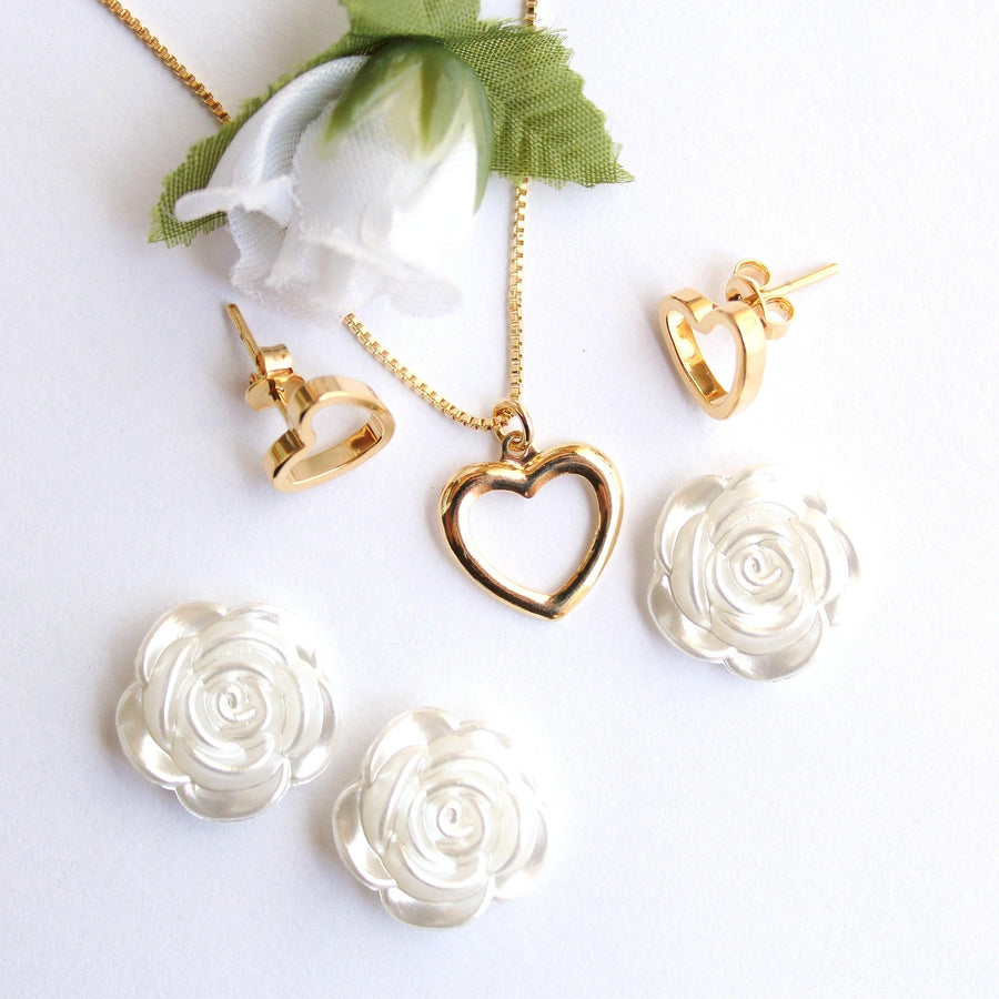 Gold heart-shaped necklace and matching earrings displayed with white floral accents on a bright white background.