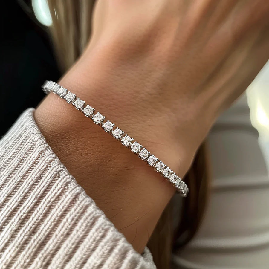 Silver tennis bracelet with round clear stones worn on a wrist.